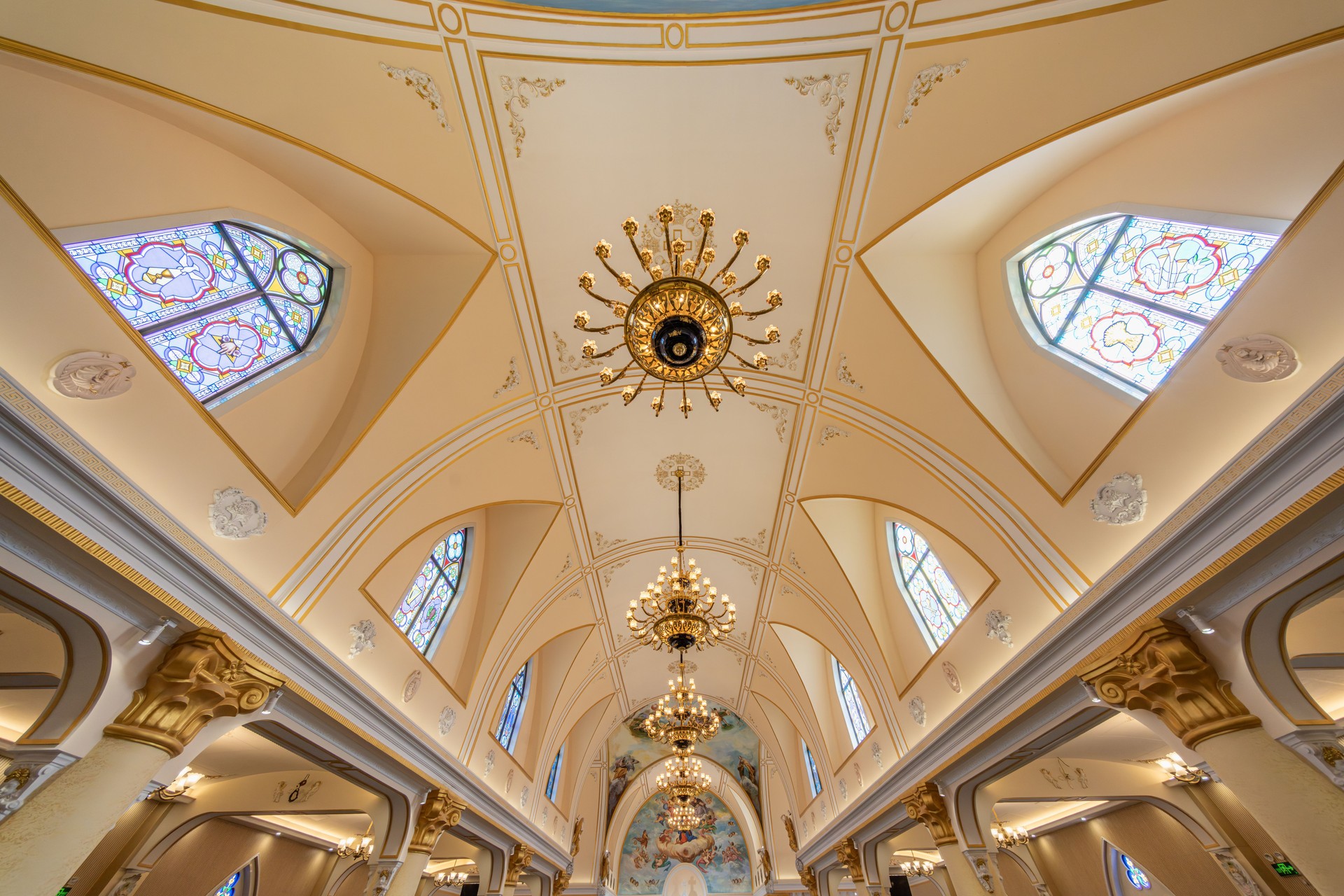 The bright and airy church ceiling with its lamps and religious motifs.